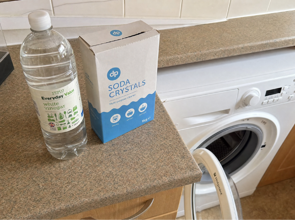 White vinegar and soda crystals next to a washing machine